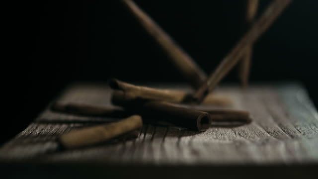 Super slow motion : A cinnamon stick falls on a black