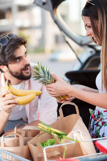 istock Playful young couple loading grocery bags into a car 969680214