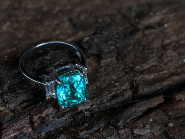 istock Closeup green gem ring with white diamond on old wooden background 969688252