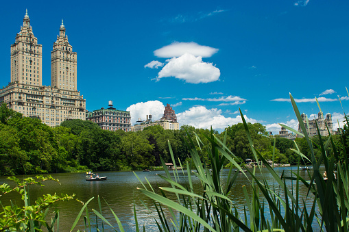 Rowing boats and a couple on a lake in Central Park, New York. The Eldorado is in the background.