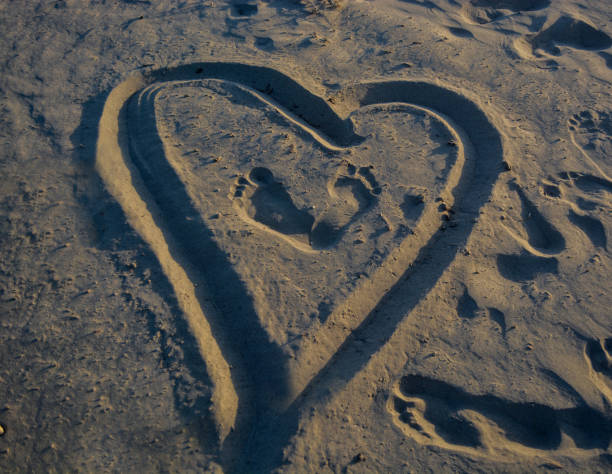 dessiner un coeur sur le sable - coeur symbole dune idée photos et images de collection