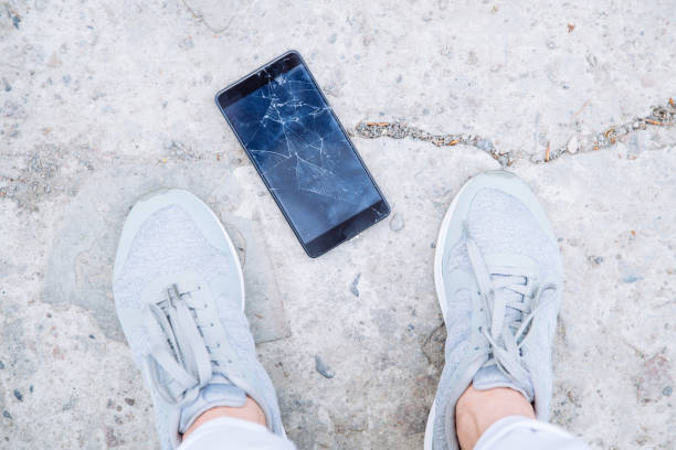 istock phone with cracked screen on ground. overhead view 969691922