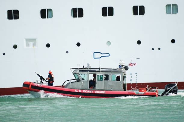 Miami - May 4, 2018: An armed US Coast Guard boat escorts a cruise ship past South Beach as it leaves PortMiami, the world's busiest cruise port.