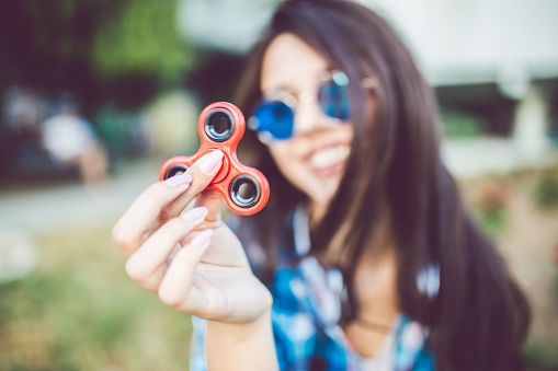 Closeup of pretty girl holding red fidget spinner