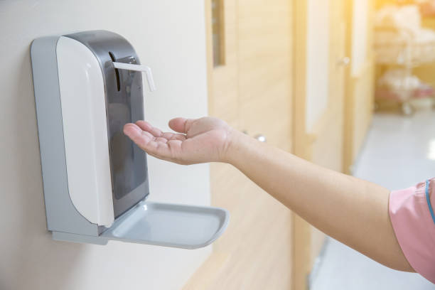 istock hands under the automatic alcohol dispenser. Infection and hospitably concept. 969695802