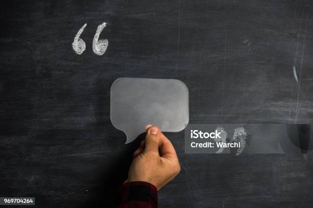 Man Holding Speech Bubble Between Quotation Marks On Blackboard Stock Photo - Download Image Now