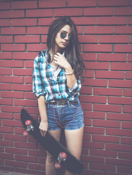 istock Girl by red brick wall with skateboard 969704270