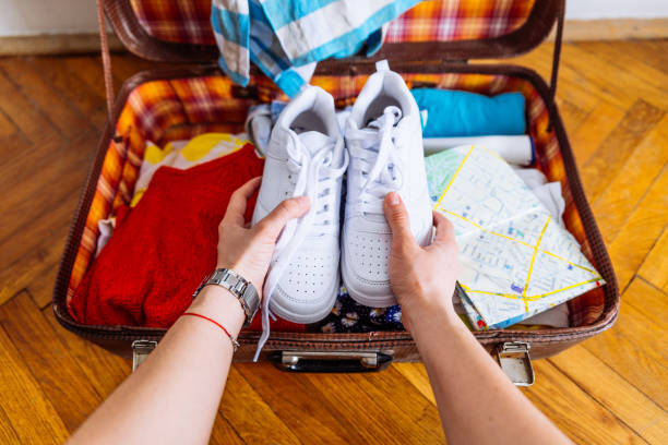 hands put sneakers to valise. packing for trip. travel concept stock photo