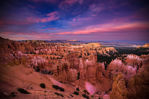 Sunlight disappears from the steep canyons and rock hoodoos of Bryce Canyon National Park on a colorful evening.