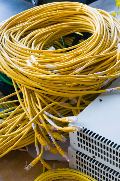 istock Jumble of yellow ethernet cables beside two network devices. 969729230
