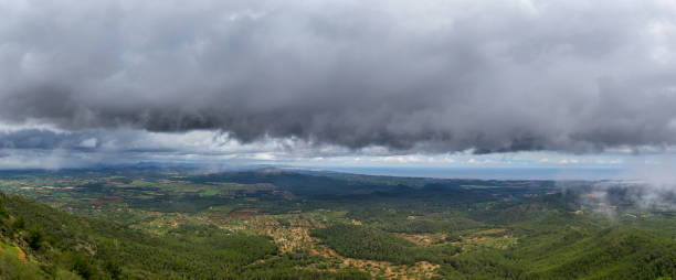 Mallorca, XXL panorama dark rainy clouds in the sky over green mountainous landscape on coastline of the island stock photo