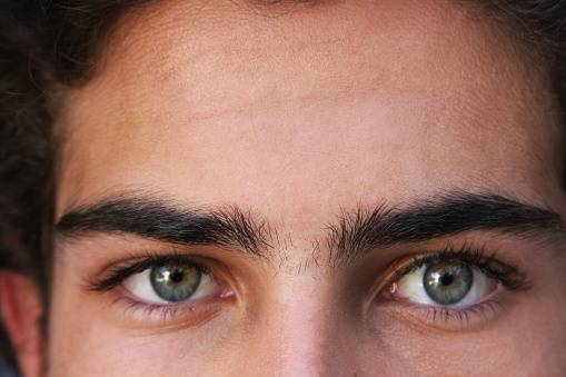 Closeup view of young man with beautiful eyes on grey background