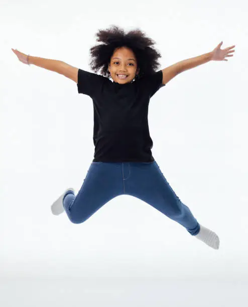 Photo of Happy and fun African American black kid jumping with hands raised isolated over white background