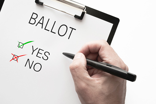 top view of ballot with choice yes or no on clipboard against white background