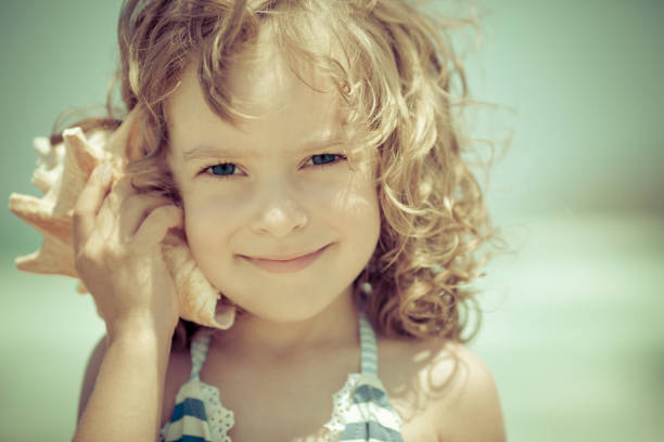 istock Happy child listen to seashell at the beach 969779710