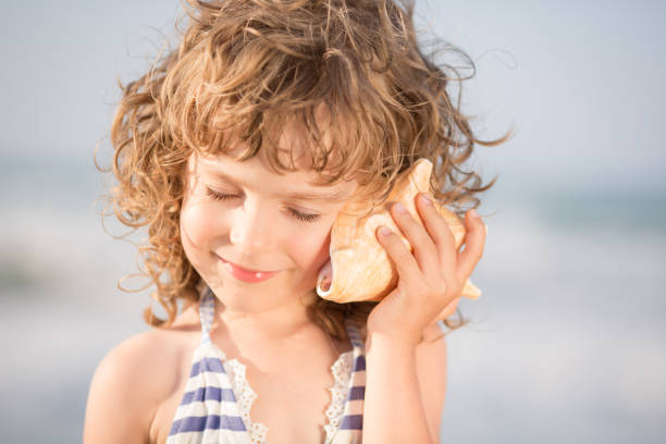 istock Happy child listen to seashell at the beach 969779768