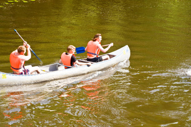 Two young women paddle a canoe on the Yellowknife River while on a camping adventure in Canada's Northwest Territories.  Click to view similar images.