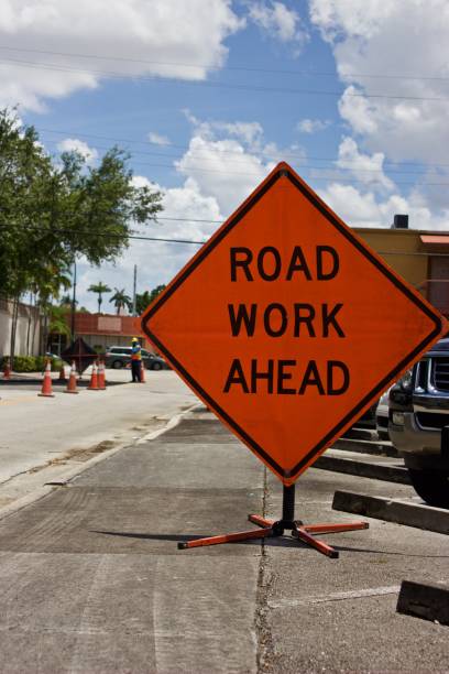 istock Road Work Ahead sign and orange traffic cones with blurred work behind 969834022