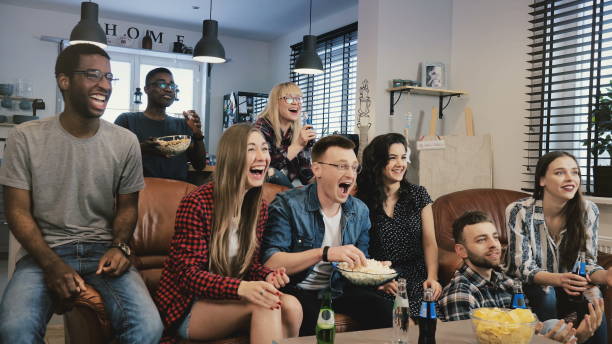 istock Multi-ethnic friends watching TV show. Medium shot. Diverse team supporters passionate and cheerful. 4K slow motion 969841286
