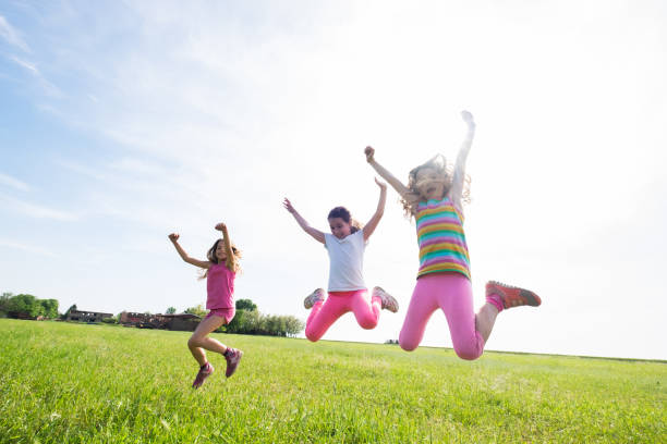 istock Three cute girls jumping at the meadow 969856102