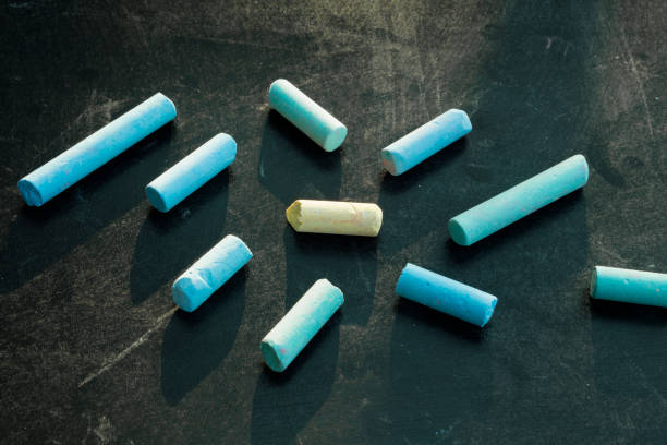 istock Group of blue chalks and a yellow one on black chalkboard. 969856348