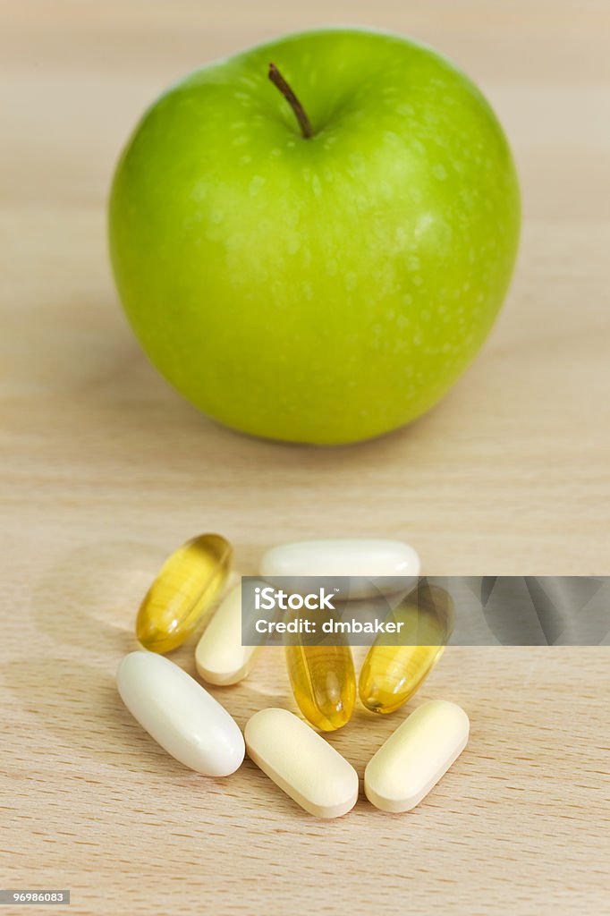 Green Apple and Nutrition Supplement Tablets or Medicine A green apple and tablets either medicinal pills or nutritional vitamin supplements. The focus is on the capsules pills and tablets in the foreground. Apple - Fruit Stock Photo