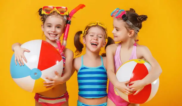 Photo of funny funny happy children in bathing suits  jumping  on colored background