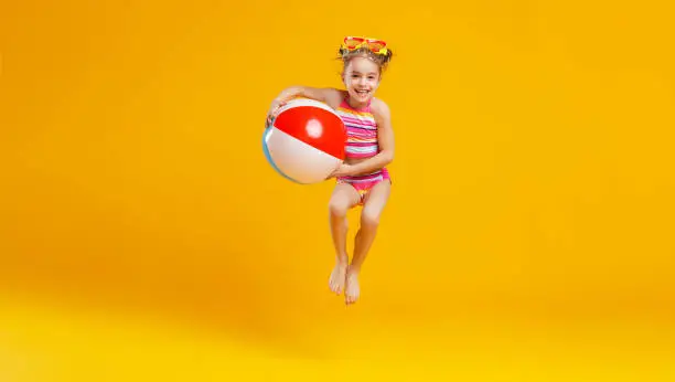 Photo of funny happy child  jumping in swimsuit    on colored background