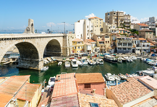 Marseille, France - May 19, 2018: View of the small fishing port of the Vallon des Auffes showing the boats, cabanons and road bridge of the Kennedy corniche with the Eastern Army memorial above it.