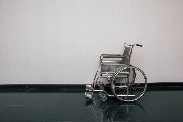 sedia a rotelle nel corridoio dell'ospedale. sedia a rotelle vuota parcheggiata in patient rooms in ospedale. - disablement foto e immagini stock