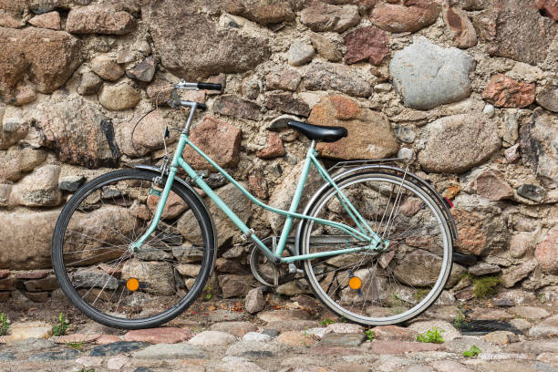 istock Old blue rusty bicycle against the old wall on the street. 969875420