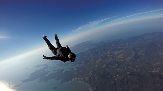 Salto de paracaidista sobre el mar y las montañas photo