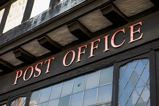 The Post Office sign above the entrance to the Post Office in the market town of Colchester in Essex, UK.