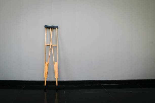 Crutches at wall.Success concept with crutches in the shadow of ladder. Crutches at wall.Success concept with crutches in the shadow of ladder. Insurance for heath care concept. Pair Of Two Crutches Leaning On White Wall. legs against the wall stock pictures, royalty-free photos & images