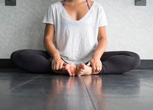 Female dancer sitting down in butterfly pose practicing yoga in the studio