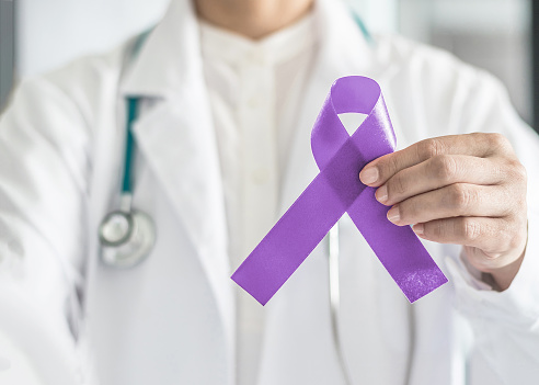 Conciencia de cinta orquídea púrpura (lavanda) en la mano del médico para (todos los cánceres de tipo), concienciación sobre el Cáncer Testicular, craneosinostosis, epilepsia, linfoma de Hodgkin, mes nacional de prevención de cáncer photo