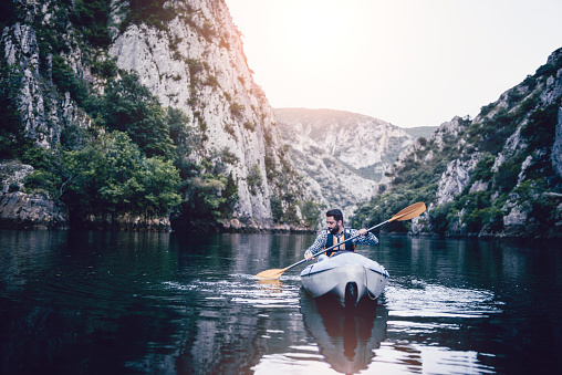 Adult Male Putting Effort To Rowing In Kayak On Lake