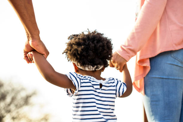 istock Little girl holding hands with her parents. 969921016