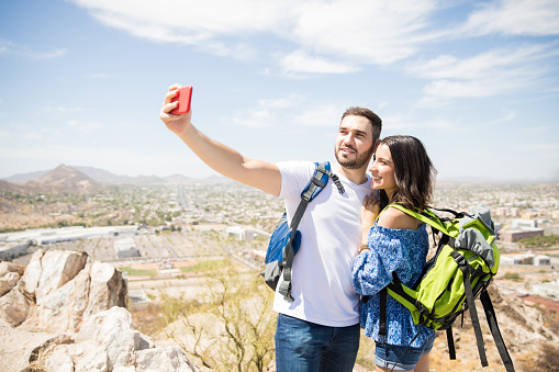 Man taking a picture of him and his girlfriend at the top of a mountain