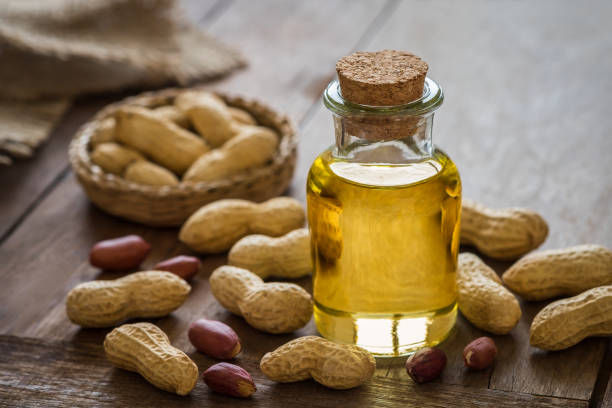 istock Peanut oil in glass bottle and peanuts on wooden table 969943552