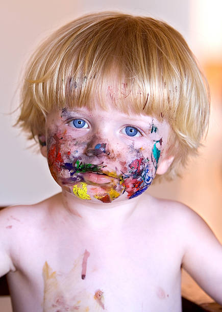 istock Young boy with face covered in colourful paint 96994376