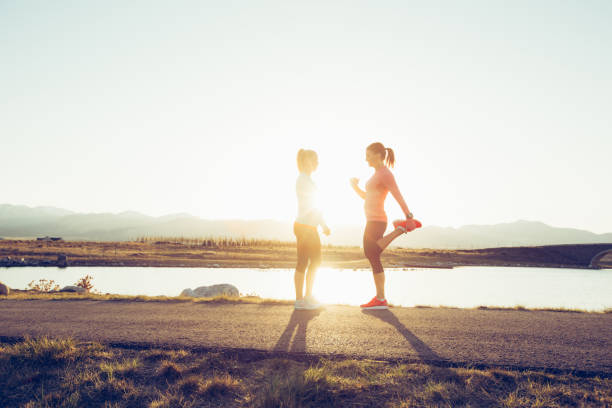 istock Two Female Runners Stretching on a Trail at Sunset 969946216