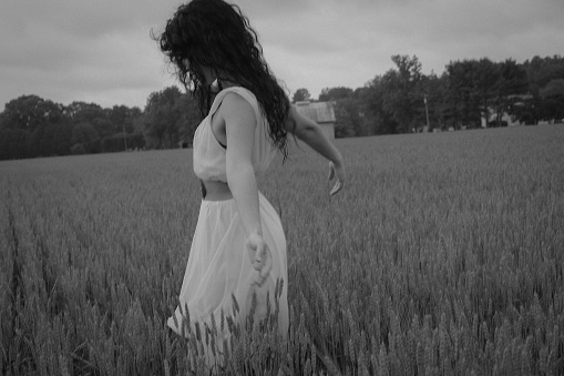 Woman Female Model in a Wheat Field Surrounded by Trees in Spring or Summer Wearing a Pink Flowing Dress