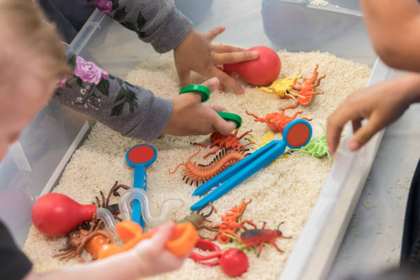 i bambini irriconoscibili giocano nel cestino sensoriale - percezione sensoriale foto e immagini stock