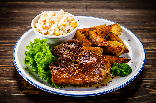 Grilled steak with baked potatoes and coleslaw