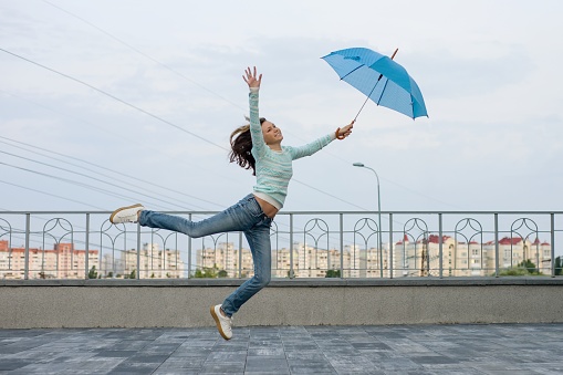 Girl is flying with an umbrella, city background.