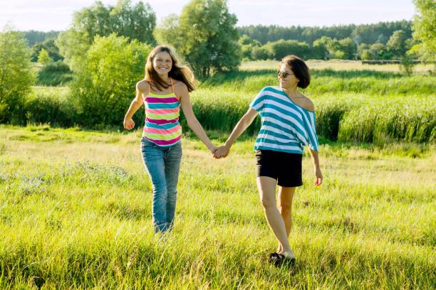 parents et adolescent, heureuse mère et teen fille 13, 14ans tenir mains aller rire parler. - 13 14 years teenager 14 15 years child photos et images de collection