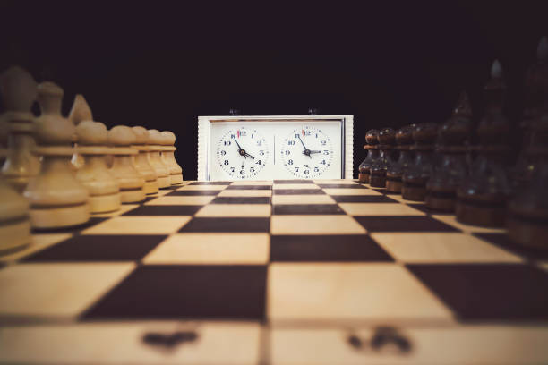 un cronómetro y un tablero de ajedrez con un juego en progreso el principio de la partida de ajedrez. el primer paso - art homage fotografías e imágenes de stock