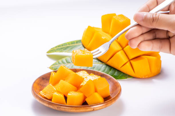 istock Fresh and beautiful mango in a wooden plate with sliced diced mango chunks isolated with   white background, copy space(text space), blank for text 970064088