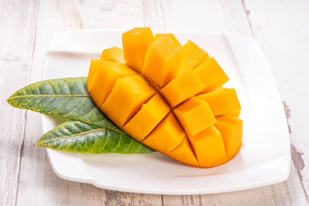 istock Fresh and beautiful mango in a white plate with sliced diced mango chunks isolated with   light wooden background, copy space(text space), blank for text 970064106
